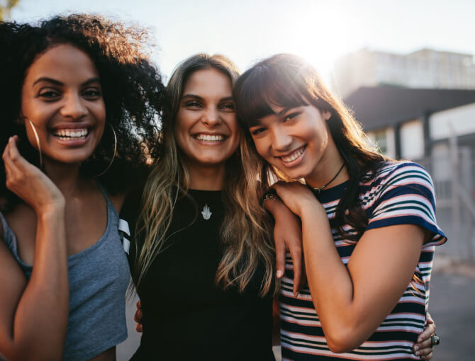 Young women friends enjoy time together outdoors in recovery from mental, emotional, and behavioral disorders.